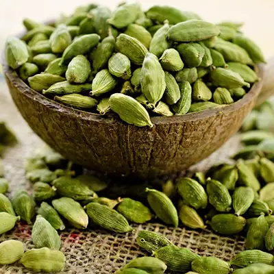 Cardamom seeds arranged in a rustic wooden bowl,highlighting their unique shape and rich color.
